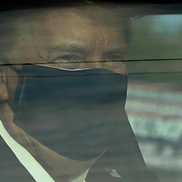 US-Präsident Donald Trump ist hinter einem Autofenster zu erkennen. Er trägt eine Maske vor Mund und Nase.