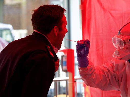 Einem Mitarbeiter der Berufsfeuerwehr Köln wird im dritten Infektionsschutzzentrum der Stadt Köln mit einem Stäbchen ein Abstrich für einen Test auf den Coronavirus entnommen.