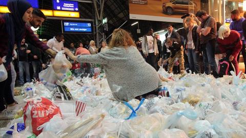 Frankfurt freut sich auf die Ankunft der Flüchtlinge: in einer beispiellosen Aktion vieler hunderter Frankfurter Bürger aller Nationen und aller Religionen werden gemeinsam Vorbereitungen für die erwarteten Flüchtlinge aus Syrien getroffen. Belegte Brote werden vorbereitet, viele fleißige Hände packen Tüten mit dem Notwendigsten, tragen Einkäufe oder Sachspenden zusammen. Über soziale Netzwerke wie Twitter, Facebook oder Whatsapp verbreitete sich die Nachricht in Windeseile und mobilisierte eine Menschenmenge, die im Verlauf des Abends den Regelbetrieb des Hauptbahnhof s nahezu lahmlegte