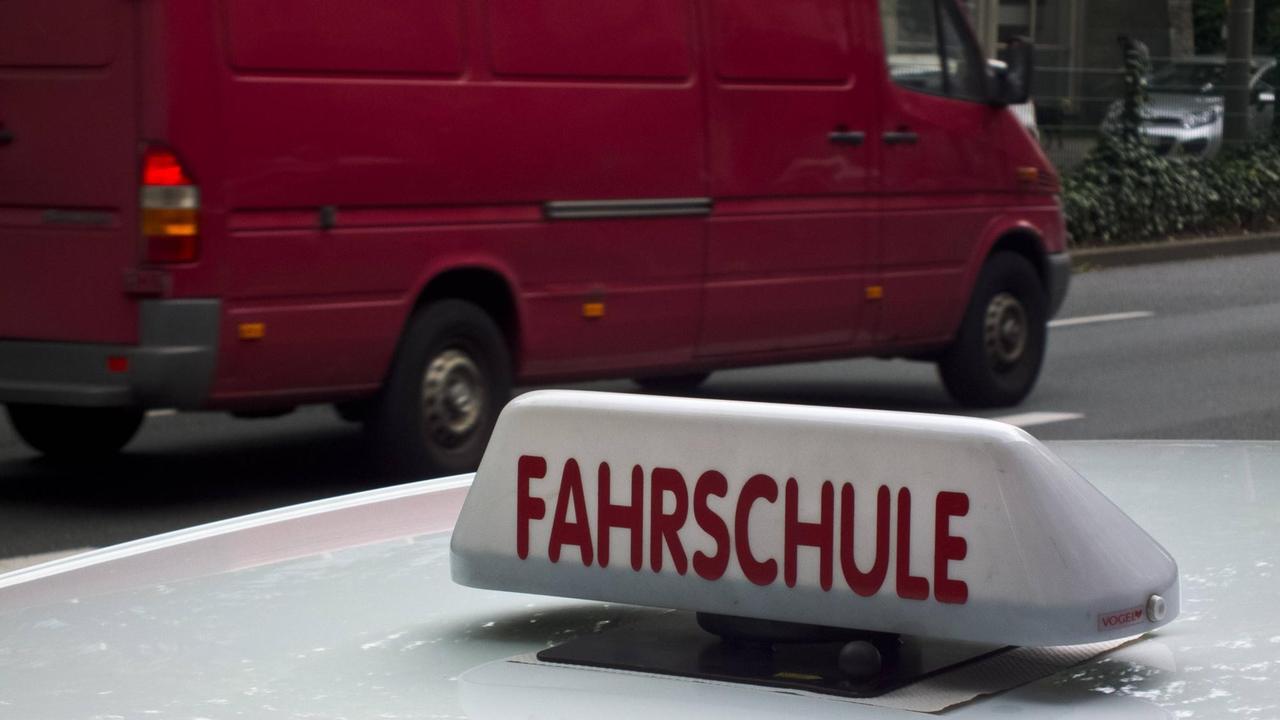 Ein Schild mit der Aufschrift "Fahrschule" auf einem Autodach.