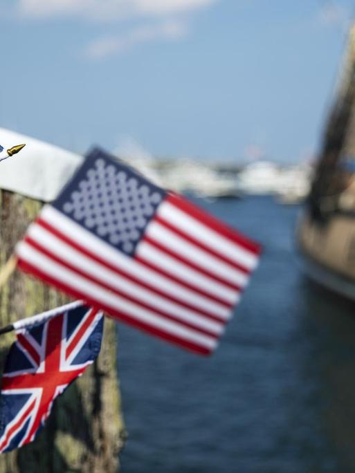 Menschen schwenken US-Flaggen und Flaggen Großbritanniens bei der Einfahrt eines der Mayflower nachempfundenen Segelschiffes