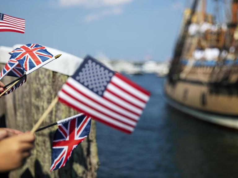 Menschen schwenken US-Flaggen und Flaggen Großbritanniens bei der Einfahrt eines der Mayflower nachempfundenen Segelschiffes