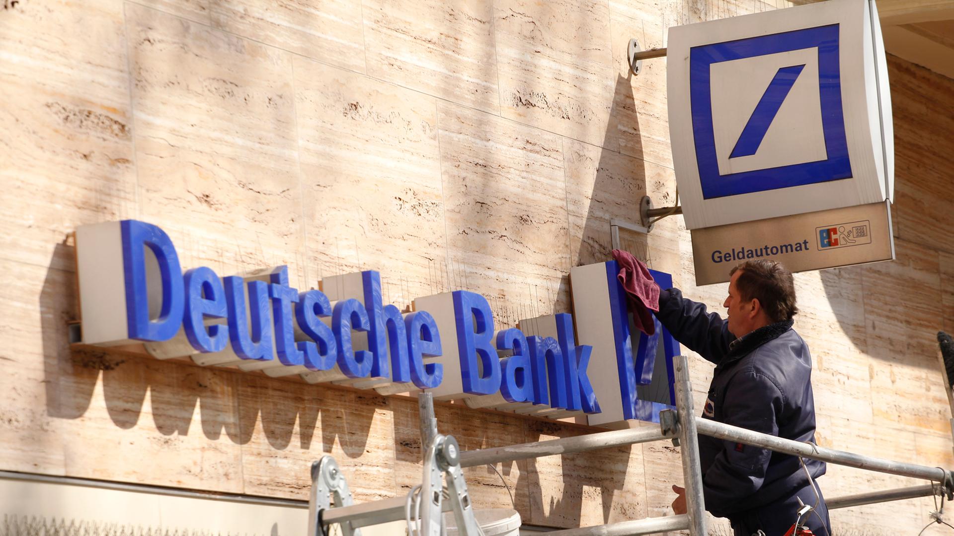 Reinigungsarbeiten an einem Deutsche-Bank-Schriftzug über einer Filiale in Berlin.