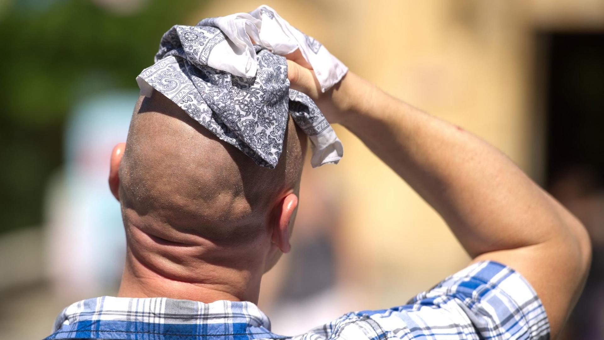 Ein Mann wischt sich am 02.08.2013 in Hannover (Niedersachsen) mit einem Stofftuch über den Kopf.