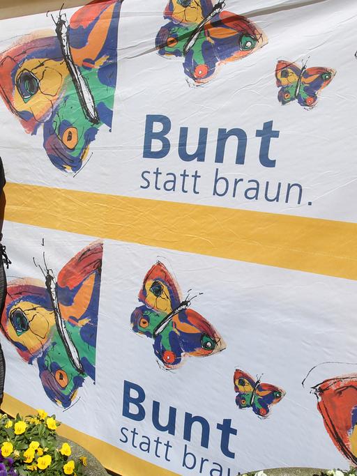 Vor der Villa Kunterbündnis in Güstrow (Mecklenbug-Vorpommern) steht am 19.04.2015 Geschäftsführerin Karen Larisch (r, Die Linke), um gemeinsam mit anderen gegen einen Aufmarsch der MVgida zu protestieren, auf dem Banner steht "Bunt statt braun".