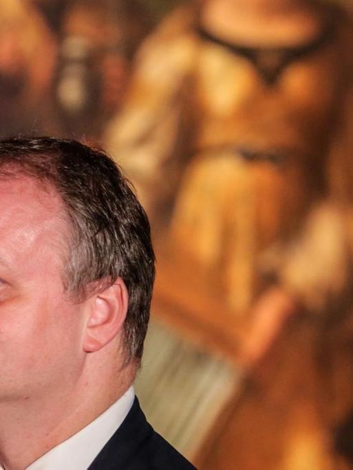 Eike Schmidt steht im Profil vor einem Gemälde Raphaels.