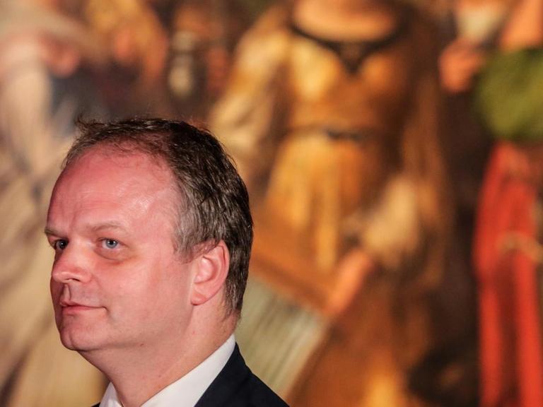Eike Schmidt steht im Profil vor einem Gemälde Raphaels.