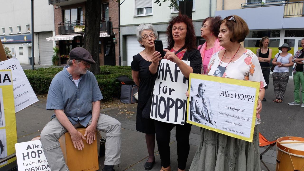 Angehörige von Colonia Dignidad-Opfern stehen mit Protest-Schildern in der Hand in Krefeld
