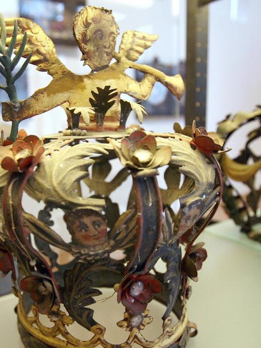 Eine Frau schaut in einem Museum in eine gläserne Vitrine, in der eine Krone steht.