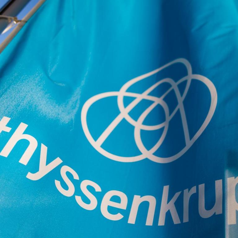 Eine Fahne mit dem Firmenlogo von Thyssenkrupp weht im Wind.