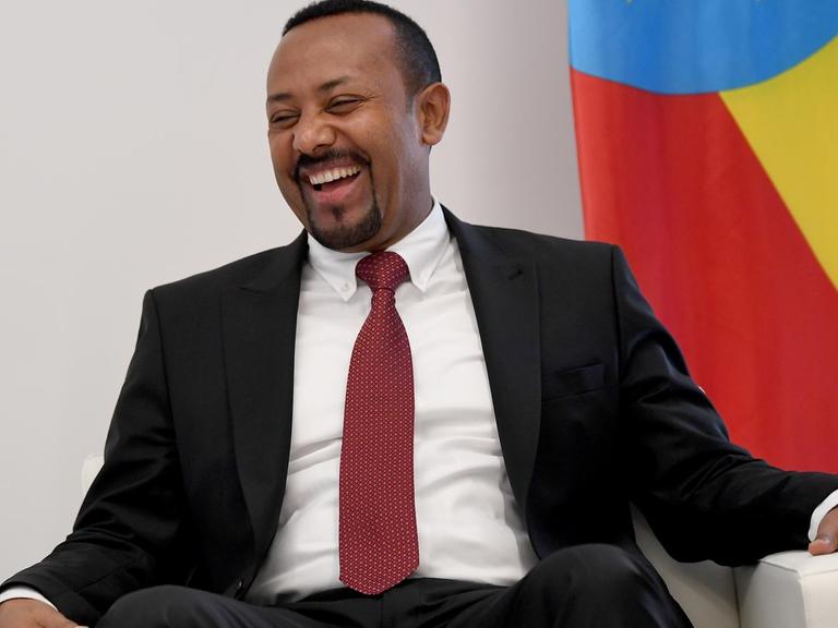Abiy Ahmed, Premierminister von Äthiopien, sitzt auf einem Sofa und lächelt.