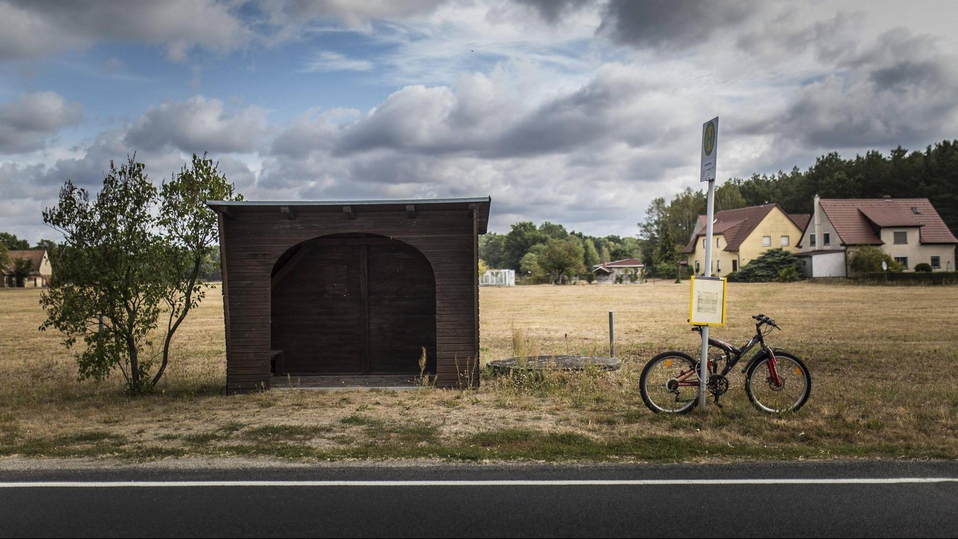 Das Foto zeigt ein Fahrrad an einer Bushaltestelle in ländlicher Region.
