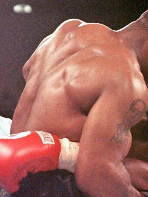 Der Weltmeister im Schwergewicht, Evander Holyfield (r), verzieht am 28.06.1997 in Las Vegas das Gesicht, nachdem ihn sein Herausforderer Mike Tyson (M) ins Ohr gebissen hat. Ringrichter Lane Mills (l) unterbricht in diesem Moment den Kampf. Tyson wurde nach der dritten Runde disqualifiziert. Nach nur dreistündiger Anhörung entschied Nevadas Sport-Kommission am Montag (19.10.1998) in Las Vegas mit 4:1- Stimmen, dem ehemaligen Schwergewichts-Weltmeister seine daraufhin vor einem Jahr entzogene Box-Lizenz zurückzugeben.