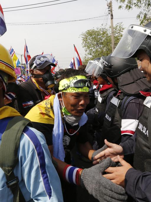 Protestler und Polizisten schütteln sich in Bangkok am 03.12.2013 die Hände