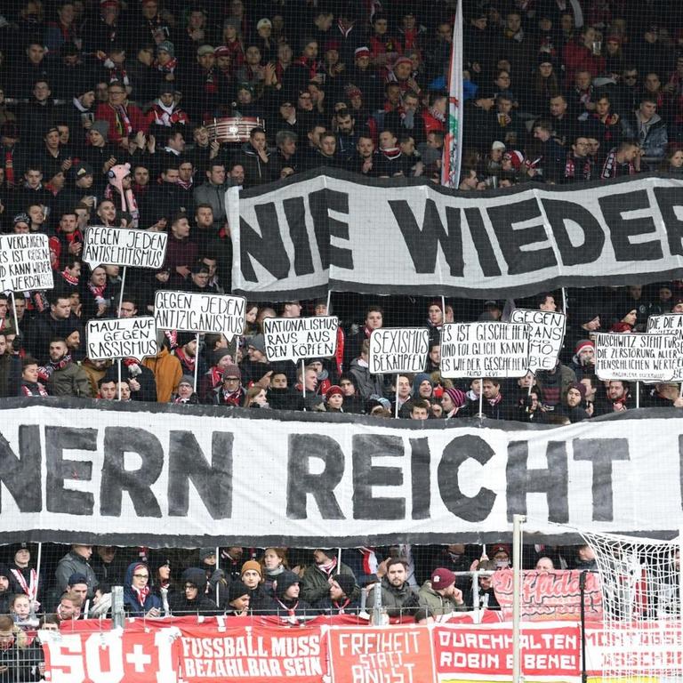 Schwarzwaldstadion: Zuschauer halten Plakate mit der Aufschrift "Nie wieder! Erinnern reicht nicht" in die Höhe.