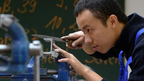 Thai Minh Nguyen aus Vietnam bearbeitet in der Metallwerkstatt des Bildungswerks der Sächsischen Wirtschaft ein Metallteil.