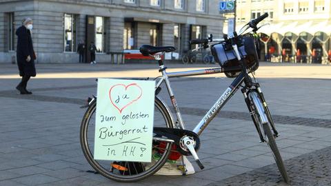 Auf einem Fahrrad ist ein Zettel angebracht, der einen gelosten Bürgerrat in Hamburg fordert.