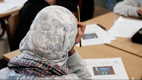 ARCHIV - ILLUSTRATION - Schüler aus Syrien werden am 12.12.2016 in einer Schule in Halle/Saale (Sachsen-Anhalt) im Rahmen eines Projektes zur Gesundheitserziehung unterrichtet. Ein Mädchen mit Kopftuch sitzt dabei an einem Tisch und hält einen Bleistift. (zu dpa «Studie «Chancenspiegel»: Jeder achte Ausländer bricht die Schule ab» vom 01.03.2017) Foto: Sebastian Willnow/dpa-Zentralbild/dpa | Verwendung weltweit