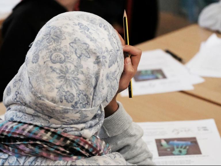 ARCHIV - ILLUSTRATION - Schüler aus Syrien werden am 12.12.2016 in einer Schule in Halle/Saale (Sachsen-Anhalt) im Rahmen eines Projektes zur Gesundheitserziehung unterrichtet. Ein Mädchen mit Kopftuch sitzt dabei an einem Tisch und hält einen Bleistift. (zu dpa «Studie «Chancenspiegel»: Jeder achte Ausländer bricht die Schule ab» vom 01.03.2017) Foto: Sebastian Willnow/dpa-Zentralbild/dpa | Verwendung weltweit