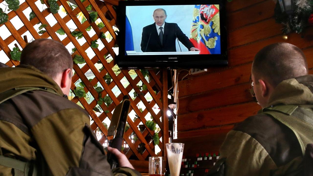 Soldaten schauen eine Putin-Rede im Fernsehen