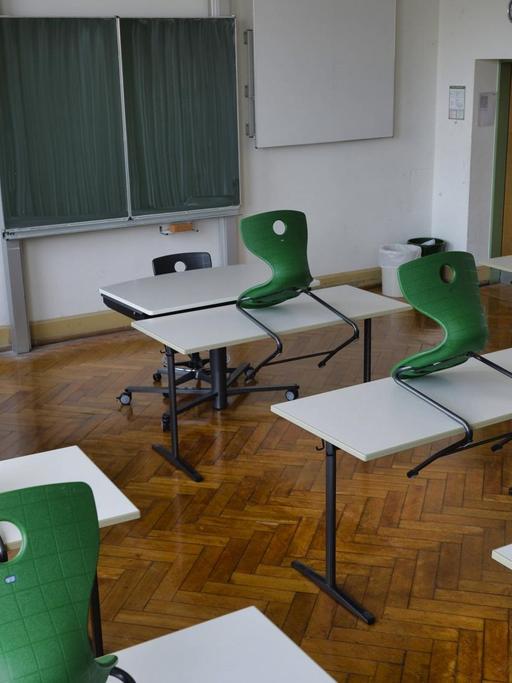 Ein leeres Klassen-Zimmer mit Tischen und hochgestellten Stühlen. 