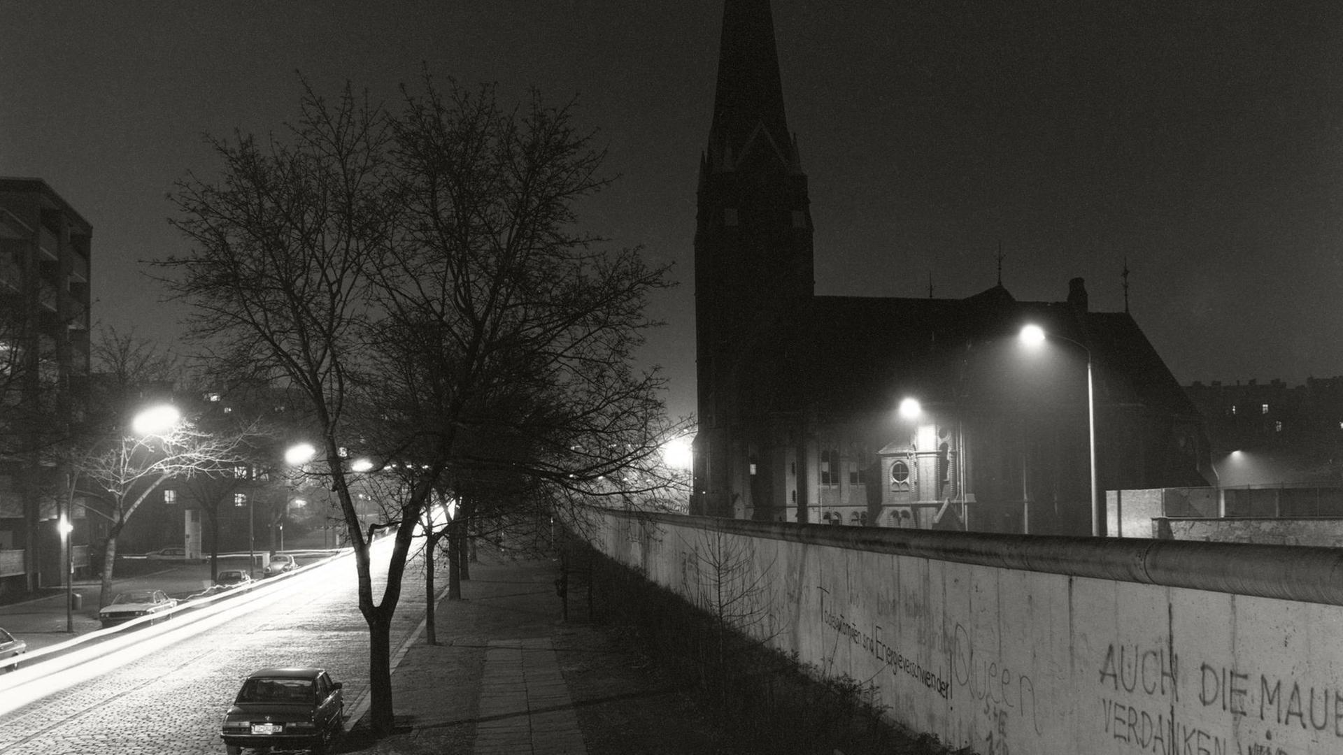Eine schwarz-weiß Aufnahme zeigt den Blick über die Berliner Mauer auf die Versöhnungskirche kurz vor deren Abriss im Winter 1985 an der Bernauerstraße am Grenzstreifen. Eine schwarz-weiß Aufnahme zeigt den Blick über die Berliner Mauer auf die Versöhnungskirche kurz vor deren Abriss im Winter 1985 an der Bernauerstraße am Grenzstreifen.