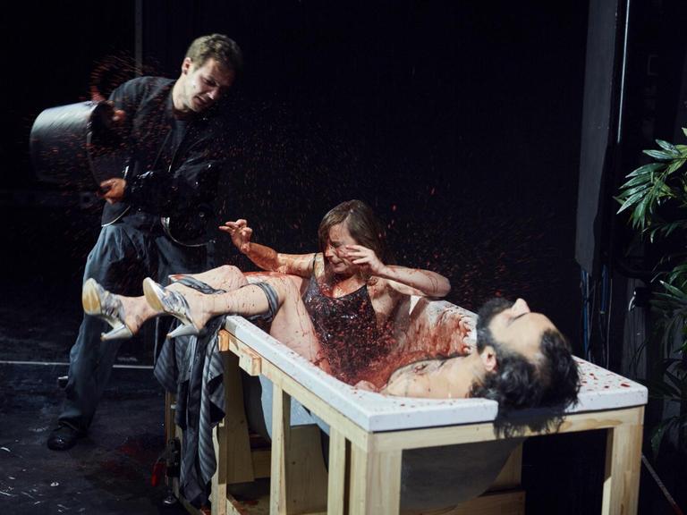 Ein Mann kippt Blut in eine Wanne mit zwei Personen.