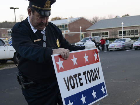 Ein Polizist stellt in Wrentham, Massachusetts, das Wahl-Schild auf