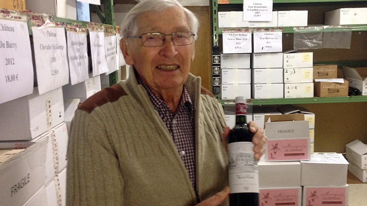 Günter Halbach aus Remscheid steht in seinem Weinkeller und hält eine Weinflasche in der Hand.