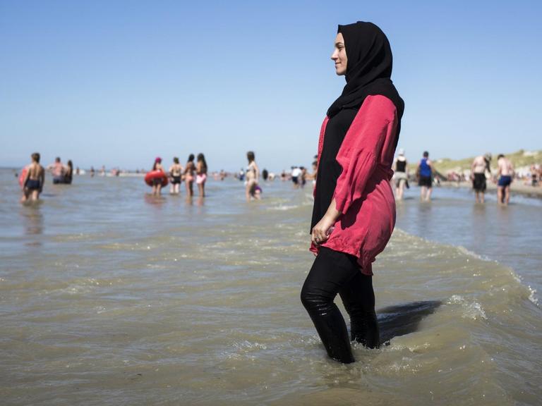 Eine junge Frau geht am französischen Strand 'Fort-Mahon' im Burkini ins Meer.