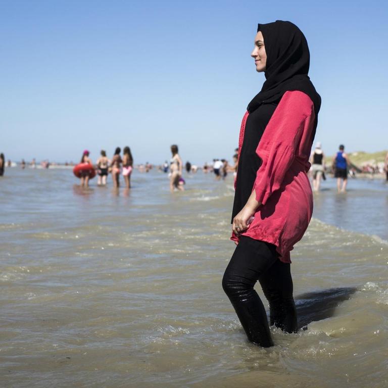 Eine junge Frau geht am französischen Strand 'Fort-Mahon' im Burkini ins Meer.