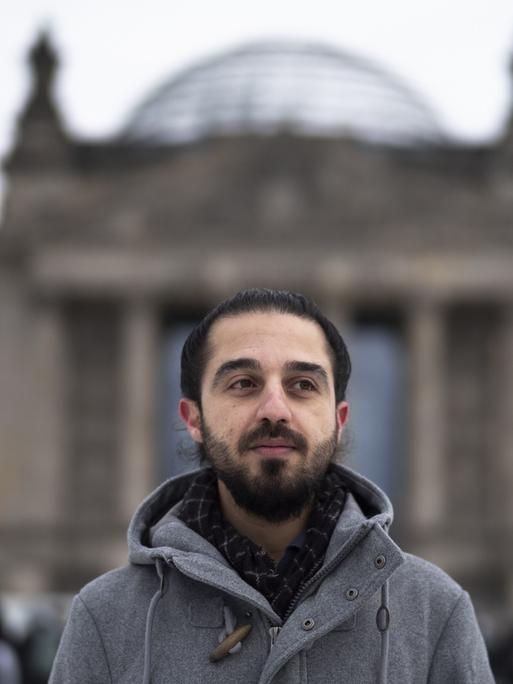 Der Grünen-Politiker Tareq Alaows vor dem Reichstagsgebäude in Berlin.