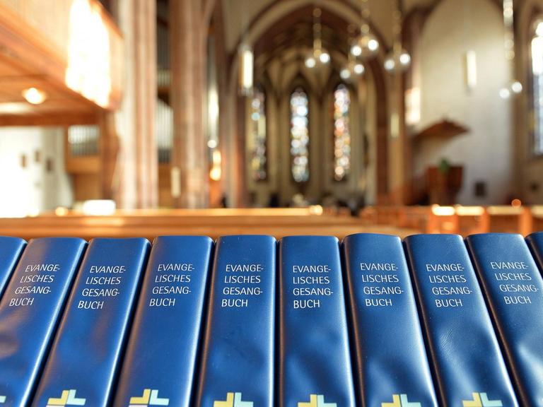 Das Bild zeigt eine Reihe von Evangelischen Gesangbüchern in der Leonardskirche in Stuttgart.
