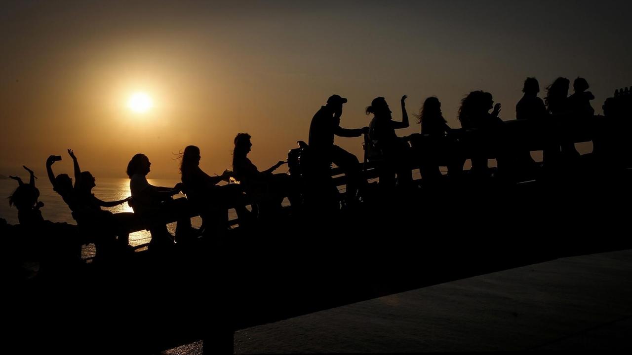 Gruppe von menschlichen Silhouetten vor der Kulisse des Sonnenuntergangs. Donostia Kutxa Kultur Festibala - Festival unabhängiger Musik in San Sebastian im Baskenland, Spanien (3.9.2016)