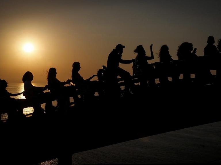 Gruppe von menschlichen Silhouetten vor der Kulisse des Sonnenuntergangs. Donostia Kutxa Kultur Festibala - Festival unabhängiger Musik in San Sebastian im Baskenland, Spanien (3.9.2016)
