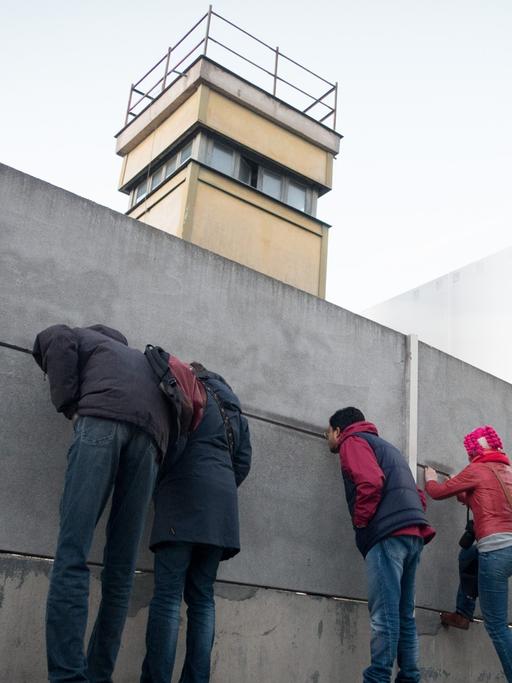 Passanten stehen an der Mauergedenkstätte in Berlin.