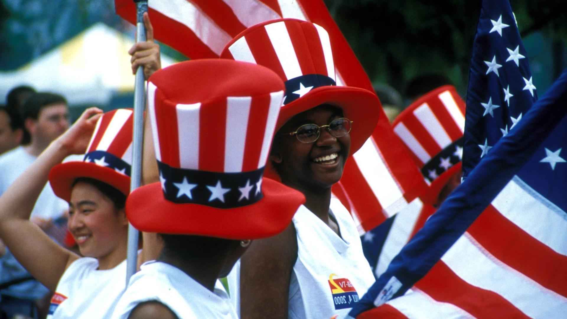 Schwarze Amerikanerinnen in Atlanta im US-Bundesstaat Georgia mit Stars-and-Stripes-Zylindern und Nationalflaggen