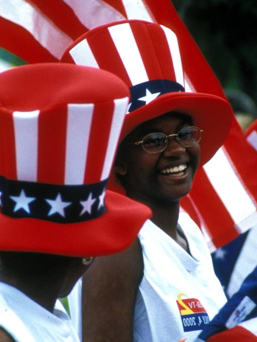 Schwarze Amerikanerinnen in Atlanta im US-Bundesstaat Georgia mit Stars-and-Stripes-Zylindern und Nationalflaggen