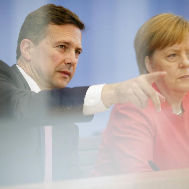 Regierungssprecher Steffen Seibert und Bundeskanzlerin Angela Merkel im Saal der Bundespressekonferenz. Seibert erteilt einem Journalisten das Wort.