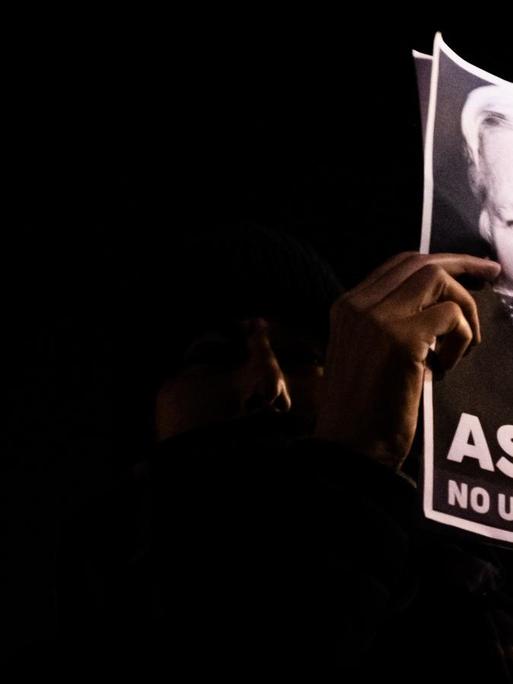 Protestierende in Paris am 05.11.2019 beim "Million Mask March" halten ein Schild von Julian Assange in die Höhe, auf dem er mit der amerikanischen Fahne geknebelt ist.