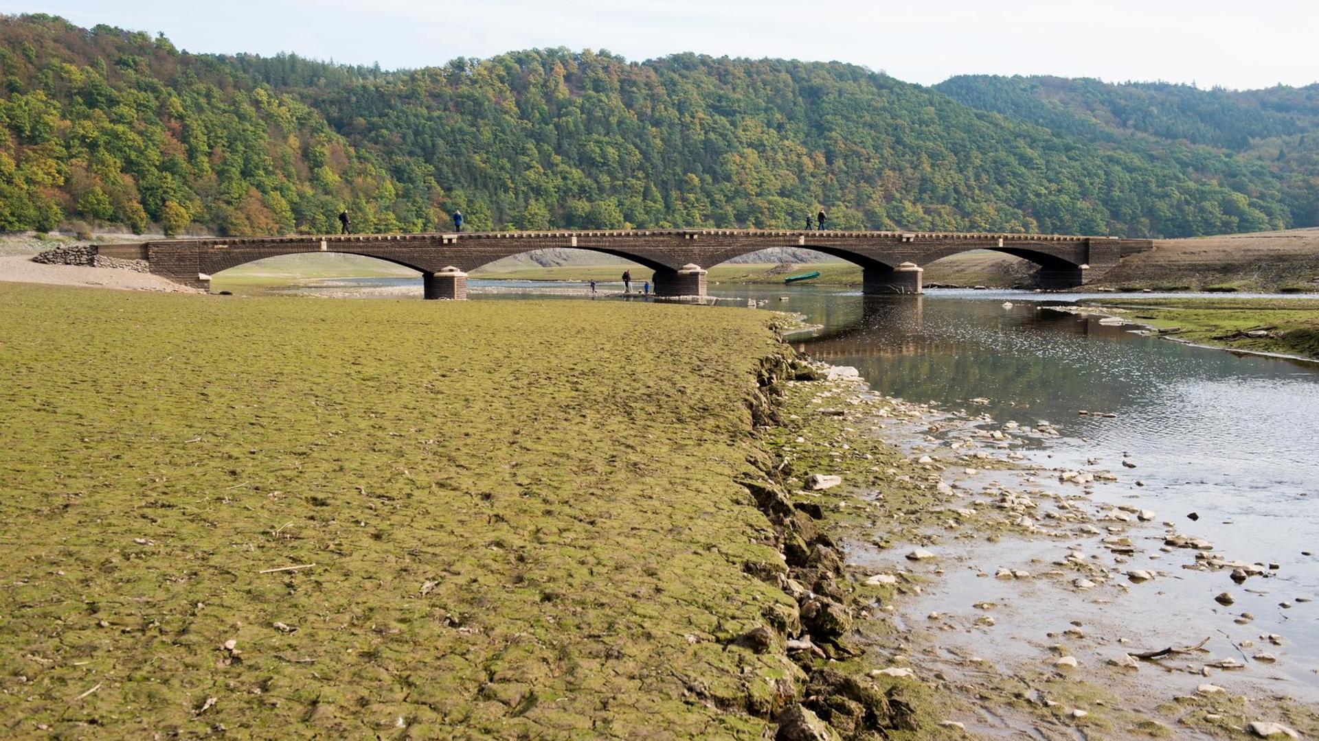 Touristen gehen am 14.10.2016 über die alte, etwa 60 Meter lange "Aseler Brücke" im Edersee (Landkreis Waldeck-Frankenberg, Hessen). Bei niedrigem Wasserstand im Edersee tauchen regelmäßig Reste alter Siedlungen auf.