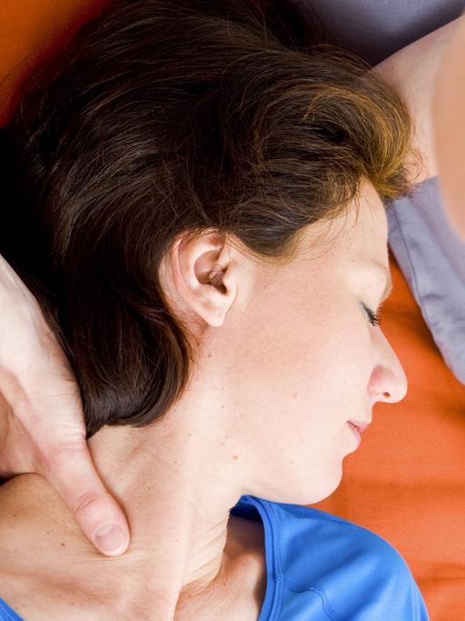 Eine Frau greift der anderen Frau während einer Körpertherapie an den Hals.