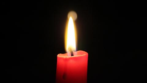 Eine rote brennende Kerze.