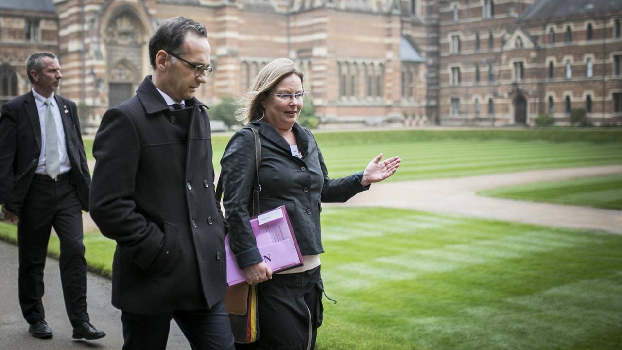 Bundesaußenminister Heiko Maas läuft links neben der sprechenden Maike Bohn, im Hintergrund eine Wiese und ein Gebäude in Oxford