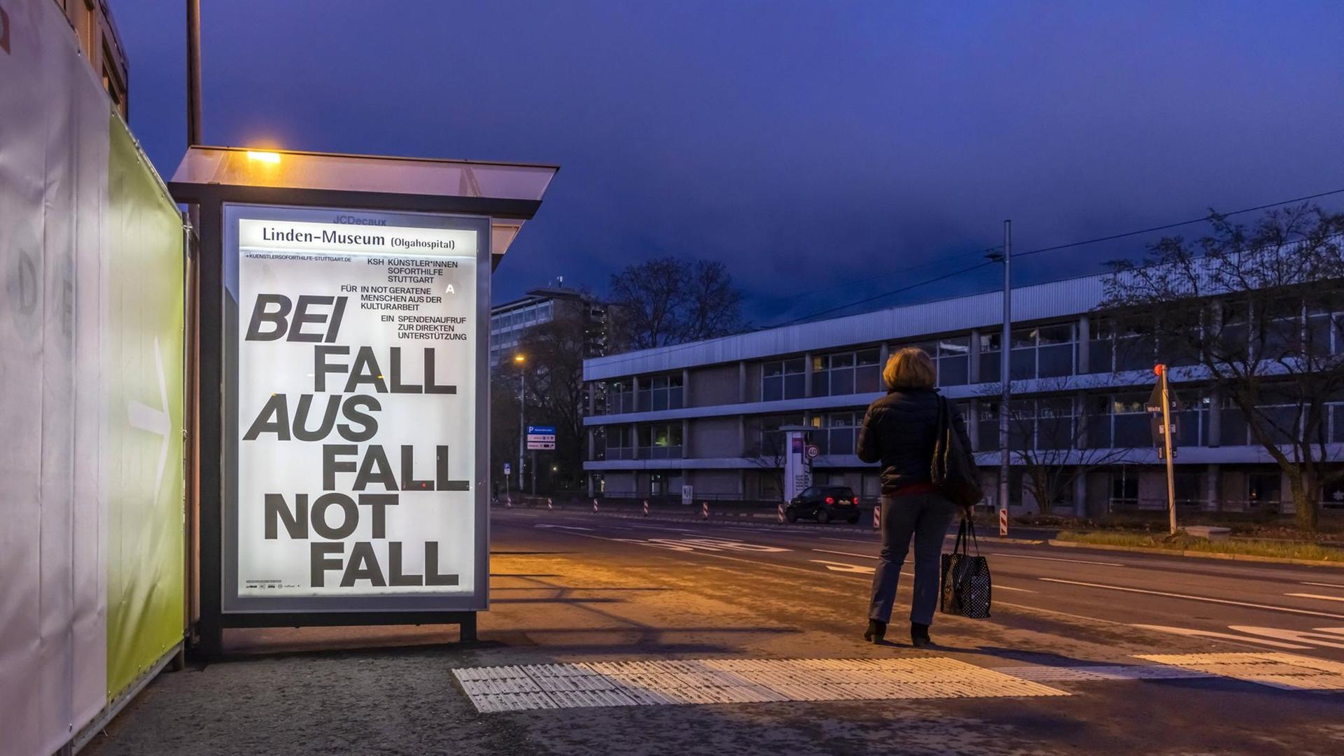 Zu sehen ist eine dunkle, leere Straße. An einer Bushaltestelle ist ein beleuchtetes Plakat mit dem Text "Beifall, Ausfall, Notfall" / 11.03.2021, Stuttgart.