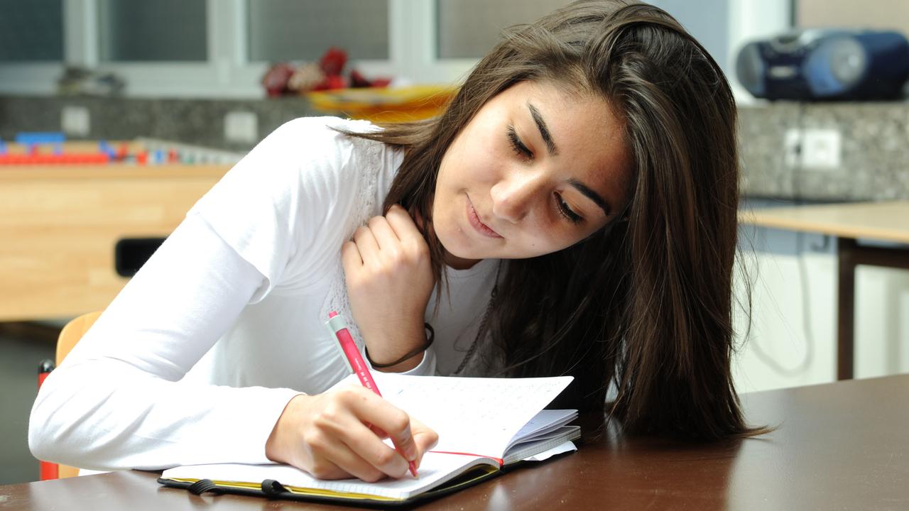 Ein dunkelhaariges Mädchen schreibt während der Schule in einem Tagebuch.