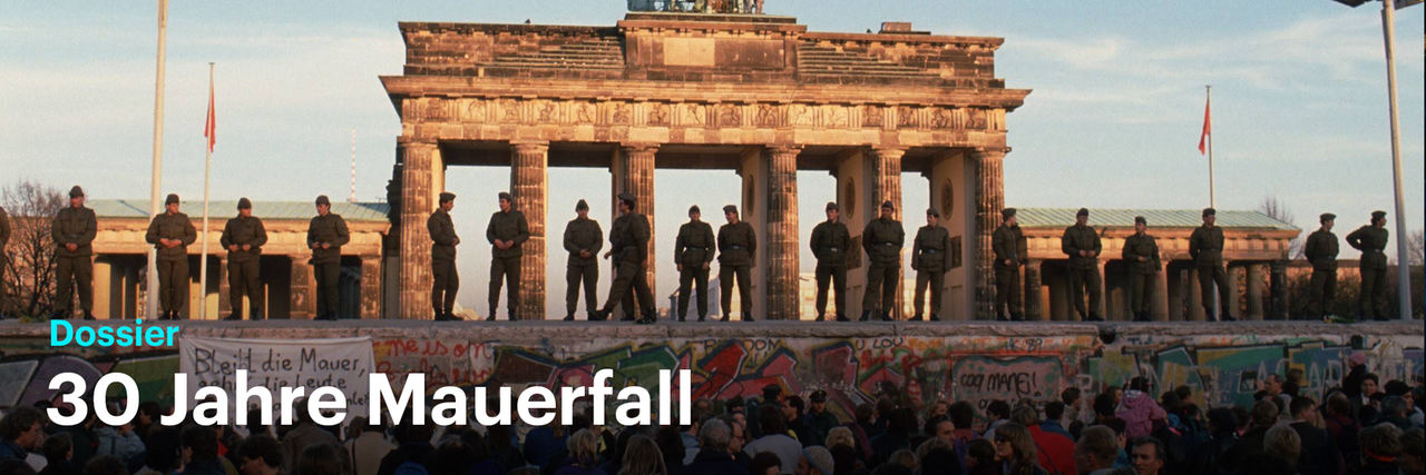 Grenzpolizisten stehen auf der Mauer vor dem Brandenburger Tor.
Durch einen Klick auf das Bild gelangen Sie zu unserem Dossier 30 Jahre Mauerfall.