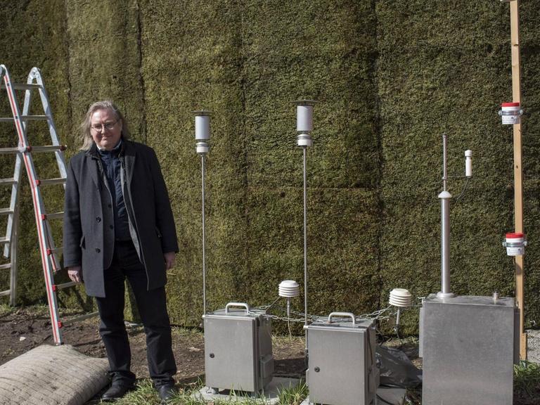 Erstmals in Baden-Württemberg ist eine Wand mit Moosen errichtet worden, um Schadstoffe und Feinstaub aus der Luft zu filtern. Die Mooswand steht an der B 14 / Cannstatter Straße. Bürgermeister Peter Pätzold direkt davor.