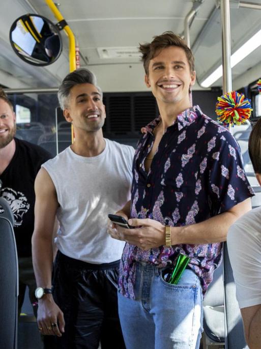 In einem Bus stehen und sitzen in fröhlicher Stimmung die 5 Akteure von "Queer Eye"