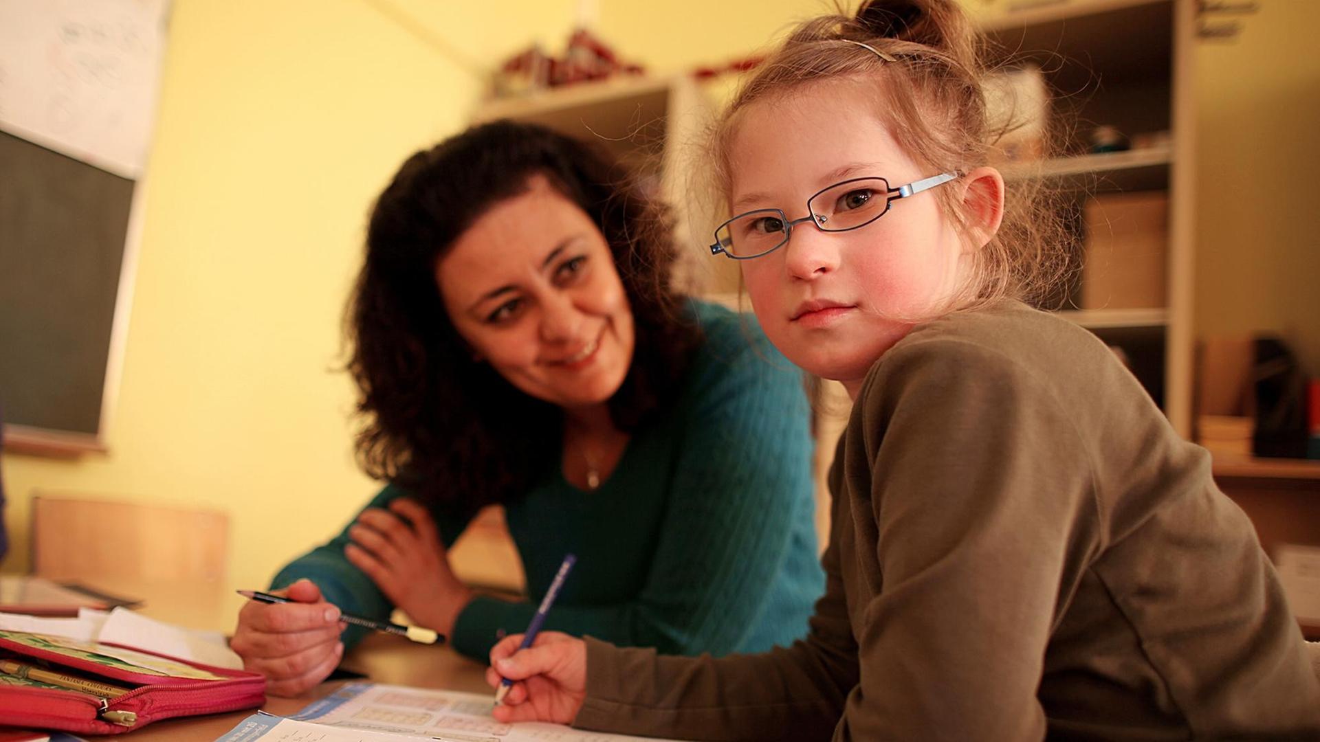 Die Inklusionshelferin Shadi Mirmousa betreut am 26.04.2017 in Aachen (Nordrhein-Westfalen) in der Gemeinschaftsgrundschule Am Höfling das Mädchen mit Down-Syndrom, Hannalena (r).